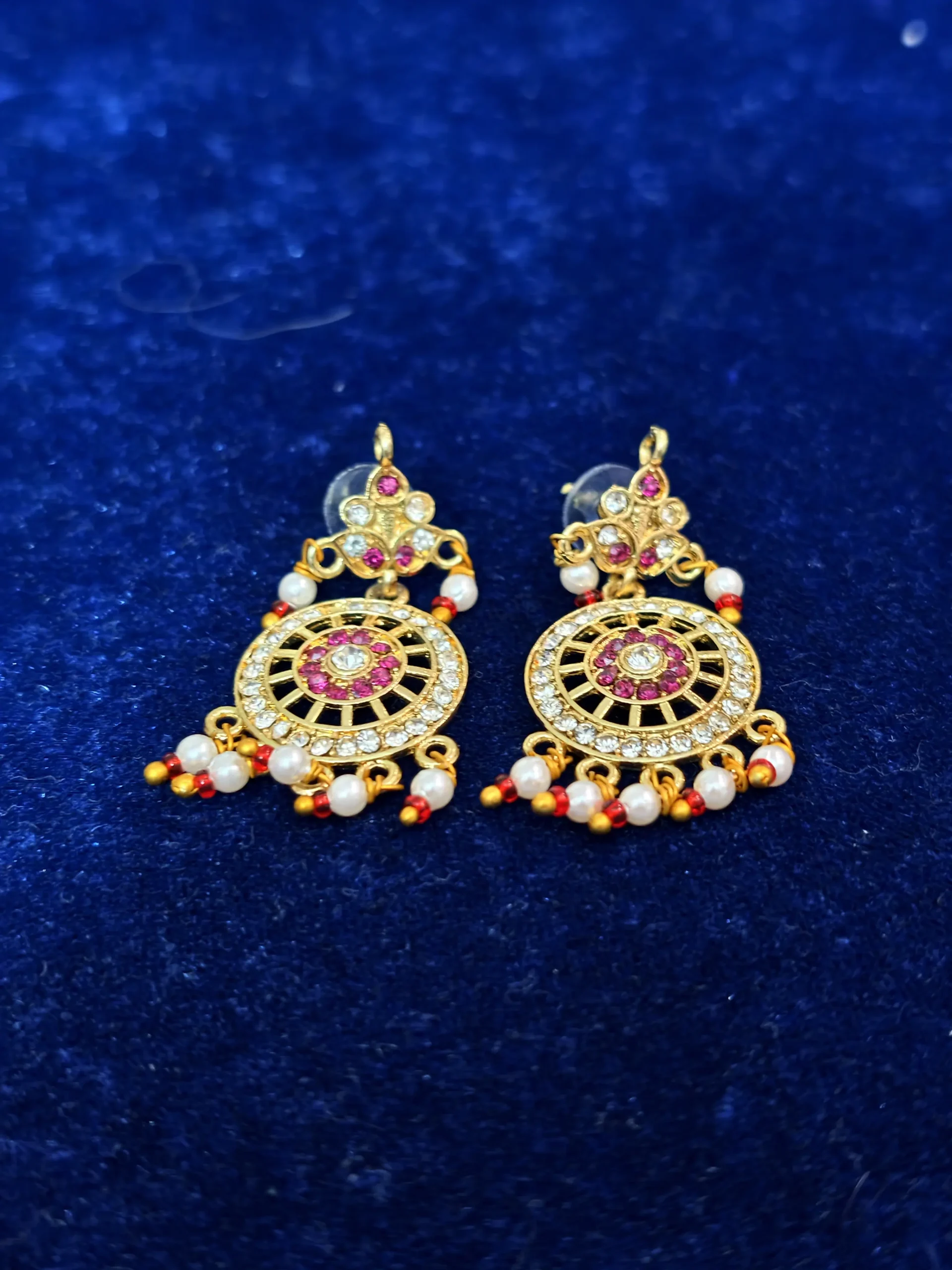 A traditional multi-strand pearl necklace set featuring a floral pendant with ruby-red and green accents, paired with matching statement earrings