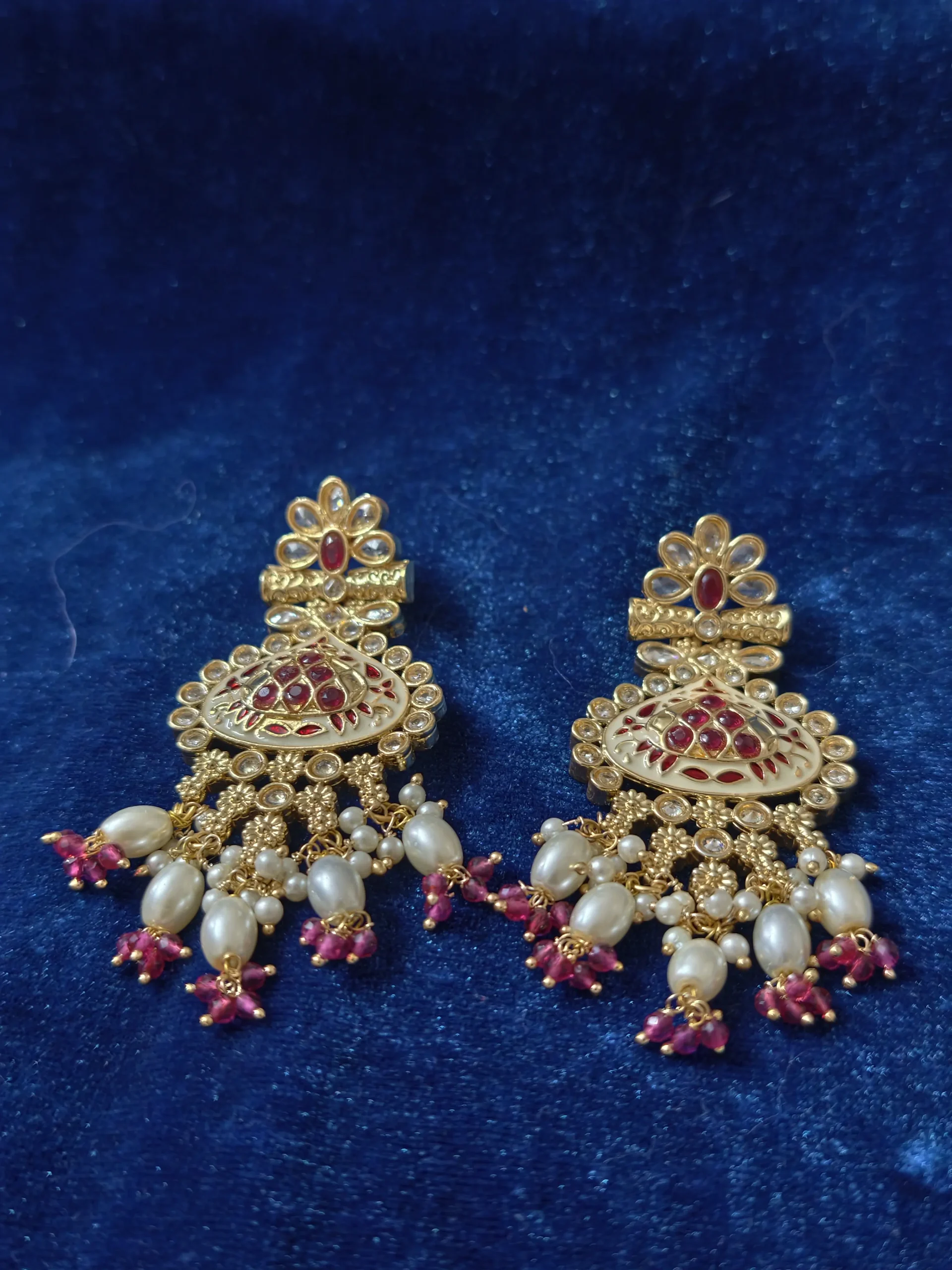 A statement pearl necklace set with ruby-red accents, an intricately detailed pendant and matching drop earrings